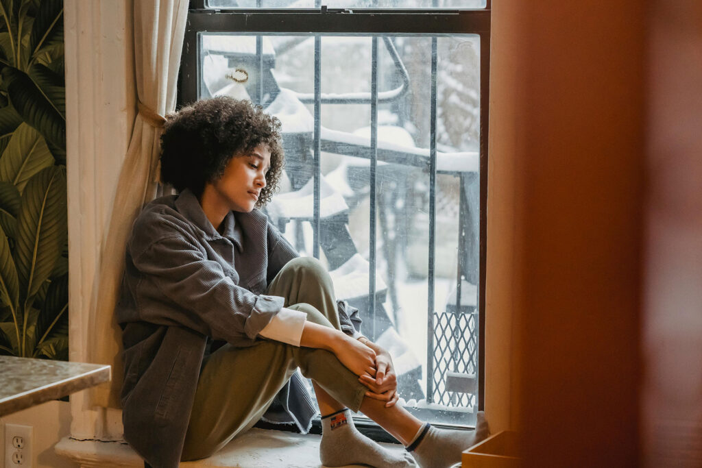 Woman sitting on window watching snow