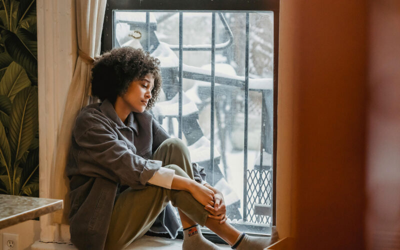 Woman sitting on window watching snow